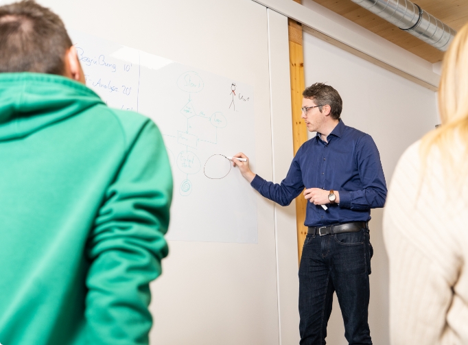 Mann schreibt auf Whiteboard