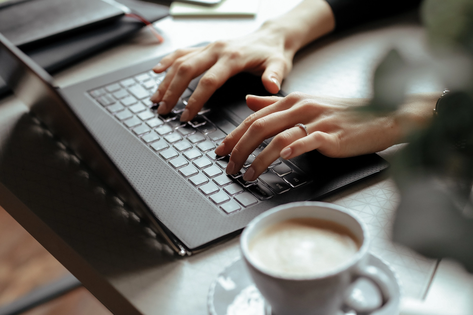 Kaffee und Laptop mit tippenden Händen darauf