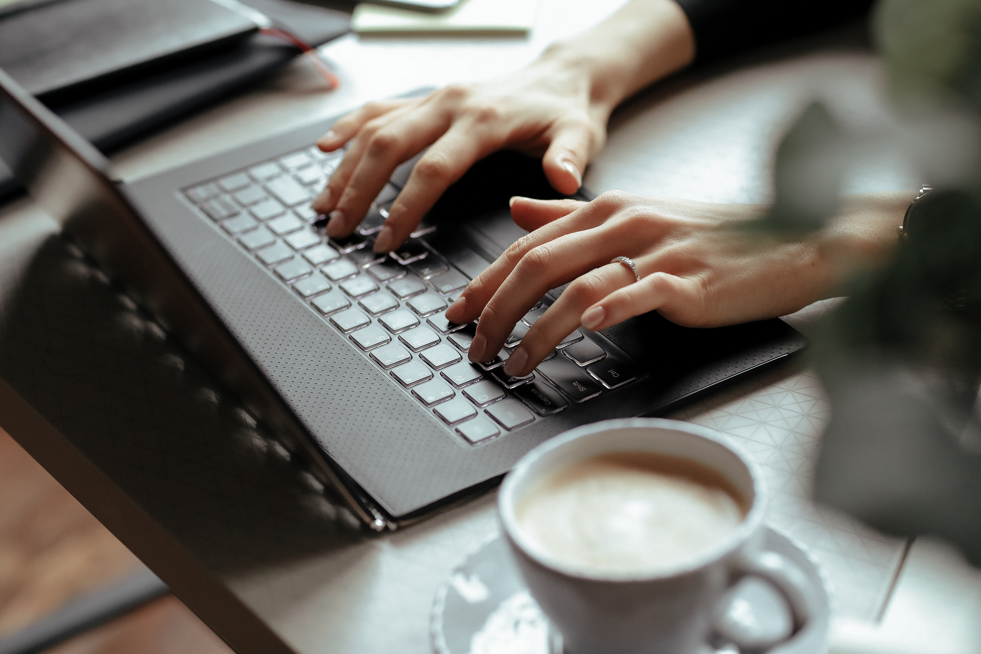 Kaffee und Laptop mit tippenden Händen darauf
